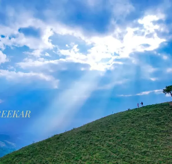 An epic drone shot of a couple on a Chikmaglur hilltop, dwarfed by the majestic landscape and heavenly sun rays. This is the kind of grand, scenic storytelling I love to create for pre-wedding films.