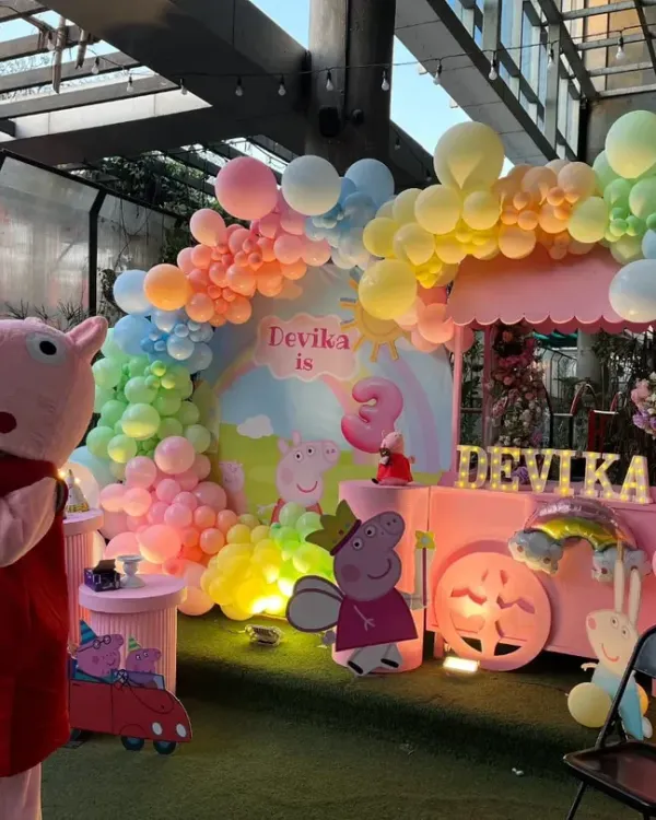A full view of our Peppa Pig themed party setup. We created a vibrant scene with a pastel rainbow balloon arch, character cutouts, and a custom-designed backdrop for the birthday girl, Devika.