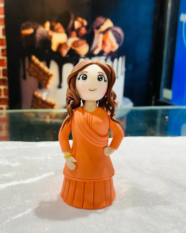 A close-up of a custom-made fondant figurine of a woman in a beautiful orange traditional dress. I can create personalized toppers to match the birthday person's likeness and outfit.