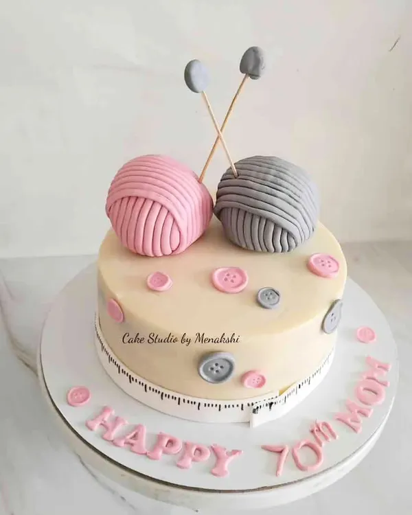 A sweet knitting-themed cake to celebrate a mom's 70th birthday. The design features edible balls of yarn, knitting needles, and buttons, all handcrafted with minimal fondant.