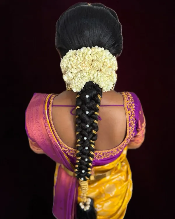 A classic South Indian bridal braid, beautifully decorated with fresh jasmine flowers and delicate pearl accessories. This hairstyle is timeless and photographs wonderfully.