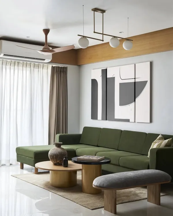 This wide view of the living room shows the L-shaped emerald green sofa, which adds a pop of natural color to the neutral palette. The space is designed for comfort and conversation, with a focus on natural textures.