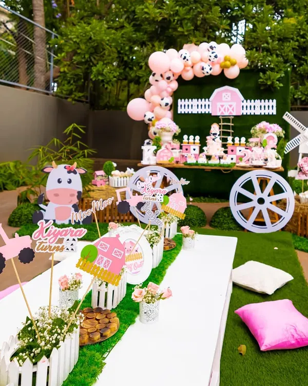 An overview of our pink barnyard party, designed for a second birthday. The setup includes a themed dessert table, a kid-friendly seating area with custom centerpieces, and charming farm animal cutouts.