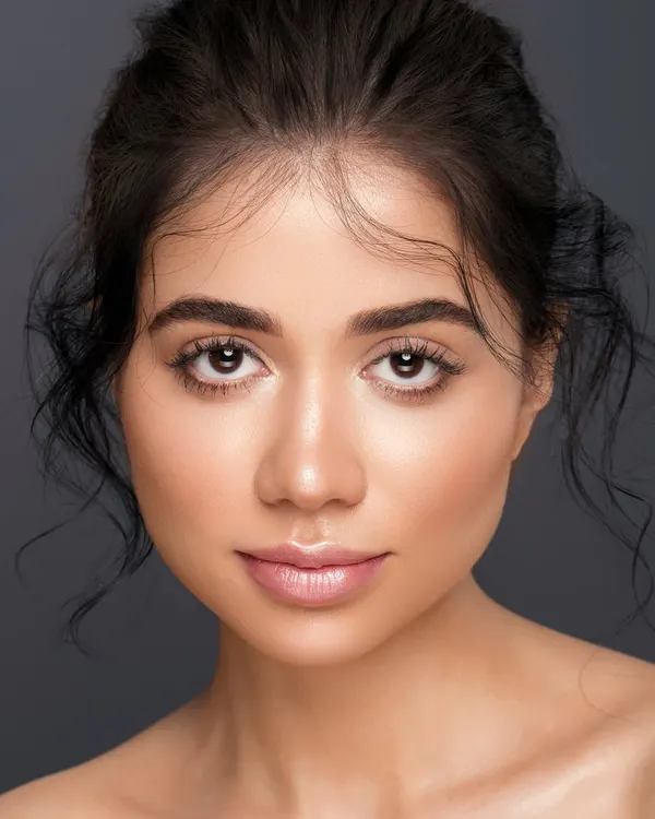 A classic headshot with a focus on clean, luminous skin and a gentle expression. The lighting is soft and even, creating a timeless portrait that is perfect for a model's portfolio.