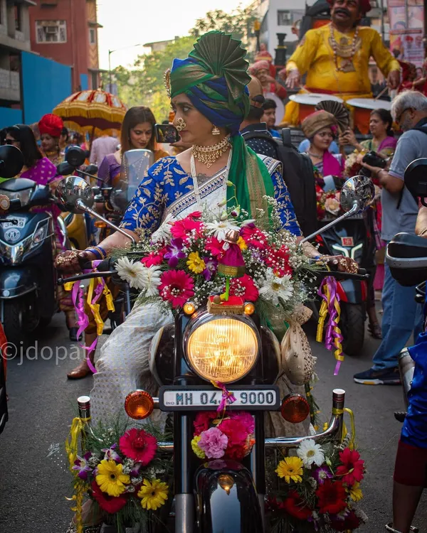 A striking image from the Gudi Padwa parade in Girgaon, Mumbai, featuring a woman in traditional Maharashtrian attire on a motorcycle heavily decorated with flowers.