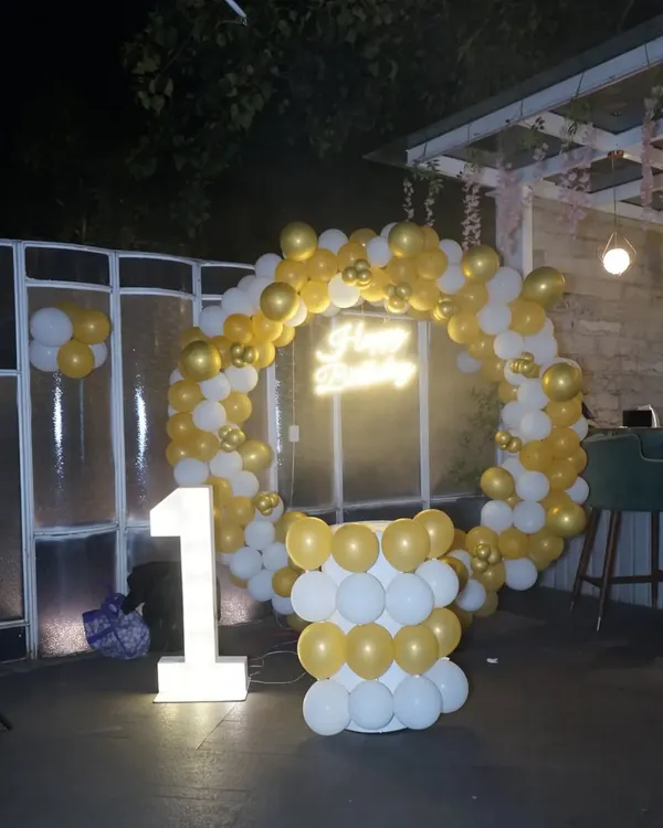 The complete setup for a first birthday party, featuring a balloon arch and a light-up number "1". We capture the beautiful decor you've planned.