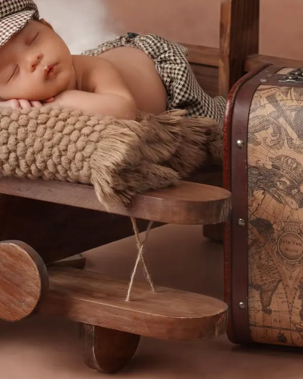 And the adventure begins. This newborn photography theme features a tiny pilot snoozing on a wooden airplane, ready to fly into his dreams. I use props like vintage-style suitcases to build a complete story.