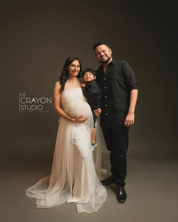 A beautiful portrait of a family on the cusp of a new chapter. The mother's serene expression, the father's proud stance, and the big brother's happy smile perfectly capture this moment before they become a family of four.