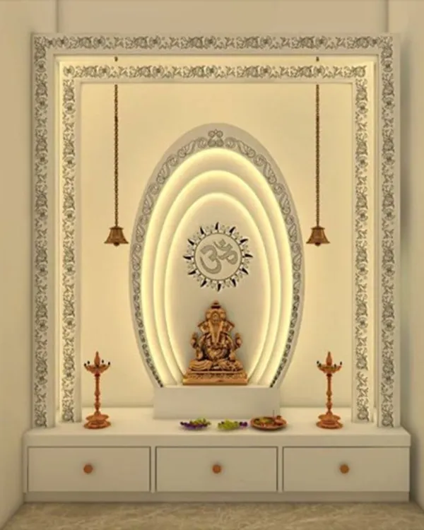 A modern home temple design featuring a backlit oval frame around a Ganesha idol, set within an intricately carved white border. This design includes built-in drawers for storage, blending functionality with divine aesthetics.