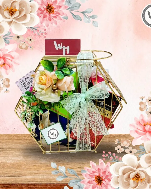 A beautiful example of a custom hamper in a unique gold-toned hexagonal wire basket. It's filled with premium teas and other goodies, adorned with delicate roses and a lace ribbon, perfect for a birthday or anniversary.