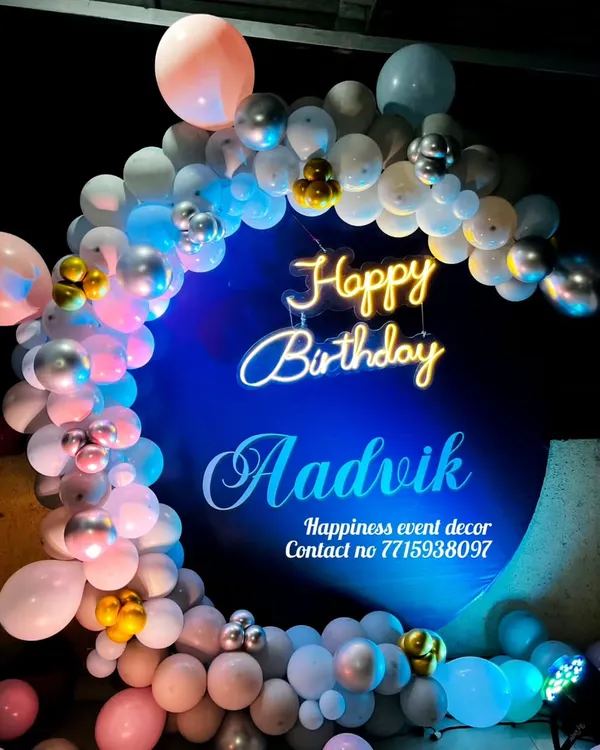I also do birthday decorations, like this custom ring backdrop for Aadivk's birthday. The setup features a personalized neon sign with the name and a balloon garland in shades of blue, pink, and silver.