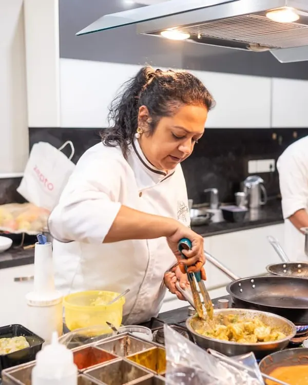 Our co-founder and chef, Sharmistha, in her element, stirring a dish in a busy kitchen during a catering event. This is where the magic begins.