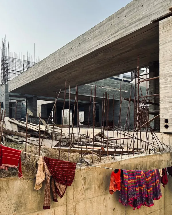 A view of the upcoming villas in Moradabad during construction. The image captures the contrast between the finished, heavy concrete cantilever and the daily life happening around the construction site.