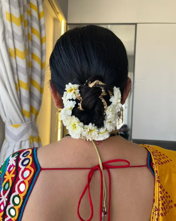 A classic and elegant low bun adorned with fresh white flowers. This timeless hairstyle is perfect for a traditional look with a saree.