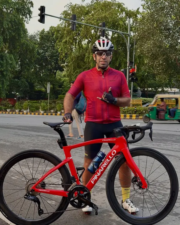 A member posing with his stunning red Pinarello road bike in the middle of a Delhi street.