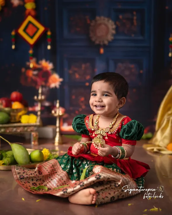 A beautiful smile from a little girl dressed in a traditional South Indian langa voni. The rich colors of her outfit are complemented by the festive backdrop, perfect for celebrating Ugadi or other festivals.