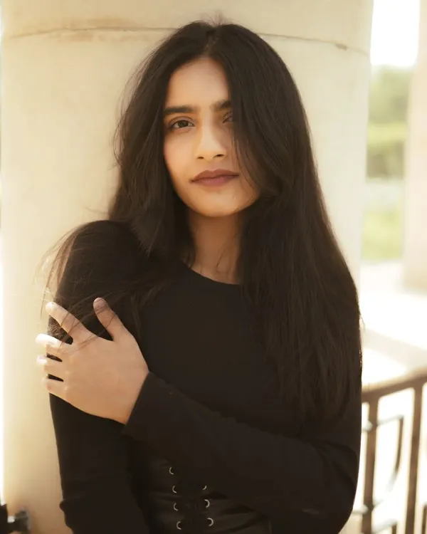 A classic portrait using the soft, natural light found in the shade of architectural pillars. The focus is on a clean composition and a genuine expression.