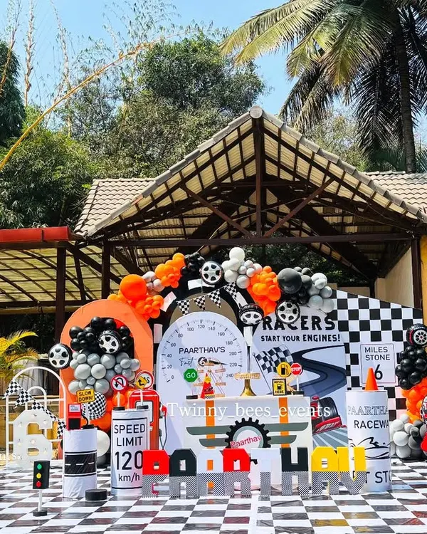 This is how we do a first birthday. We created a full-scale outdoor car racing theme, complete with a chequered floor, custom racetrack backdrop, and themed props like traffic cones and fuel barrels for Paarthav's big day.