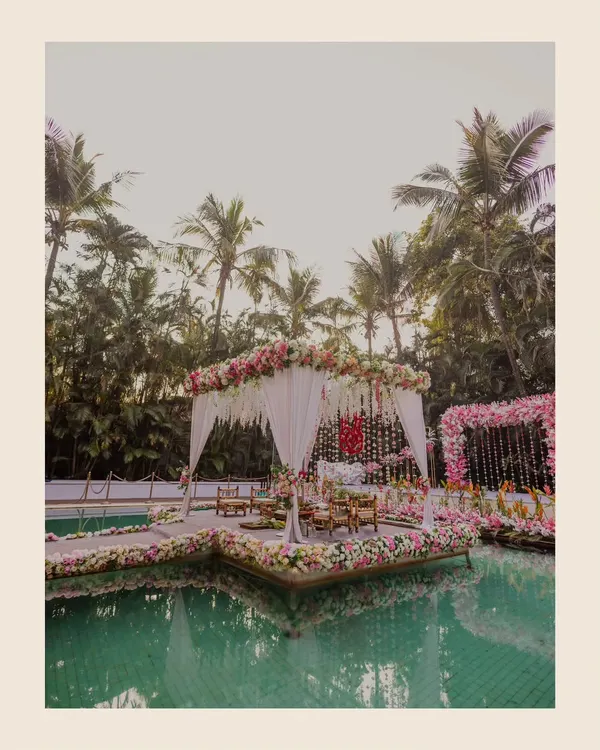 A breathtaking view of a wedding mandap floating on a pool at the Exotica resort in Thane. The floral decorations and serene water create a dreamlike setting for a Maharashtrian wedding.