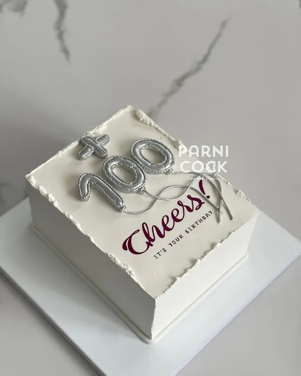 A cake to celebrate a century of life! This minimalist rectangular cake features silver balloon-style numbers for a "100th" birthday, proving that style is ageless.