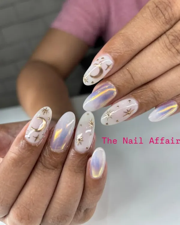 This celestial-themed design features an iridescent base with hand-painted stars and moons, accented with 3D metallic charms for a magical finish. It's a perfect example of our detailed, multi-layered nail art.