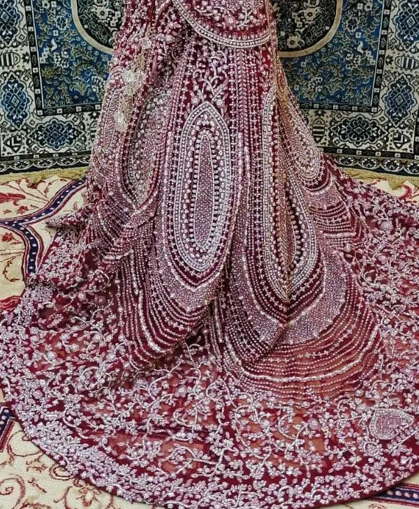 A close-up of the trail of a Pakistani-inspired bridal outfit. The intricate silver and pearl beadwork on the deep wine fabric is absolutely breathtaking.