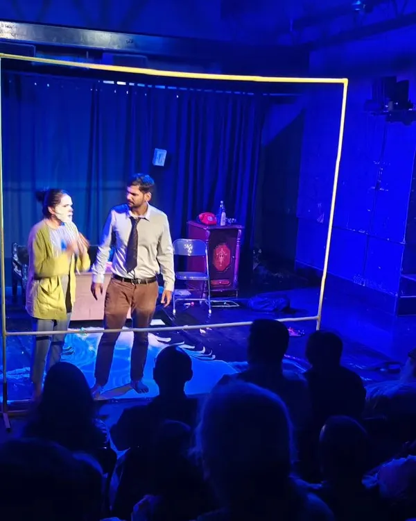A dramatic scene from a Vyoma Actors Studio (VAS) student production. The striking blue lighting and minimalist set focus all attention on the actors' intense interaction.