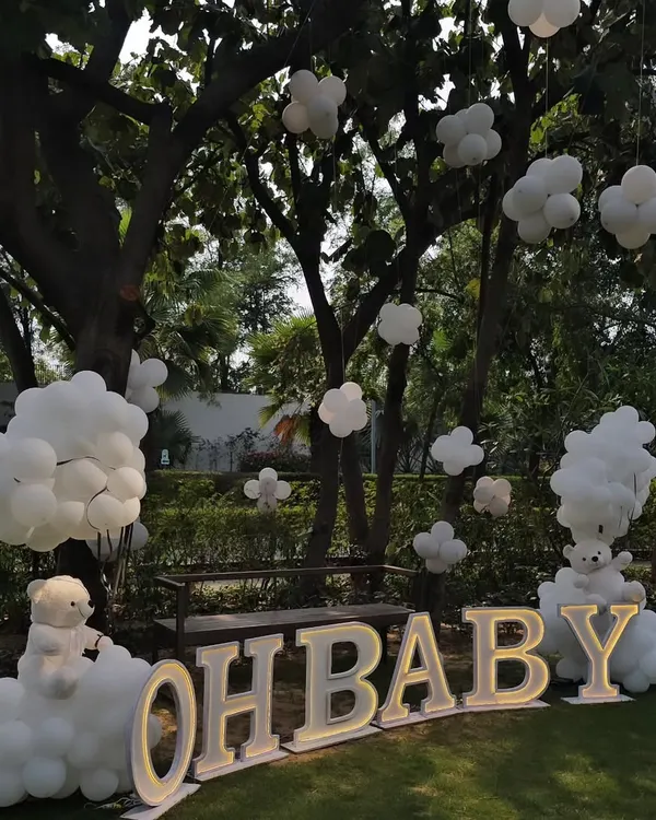 A dreamy outdoor 'Oh Baby' shower with a teddy bear and cloud theme. The large marquee letters and balloon clouds create a beautiful photo backdrop in a garden setting.