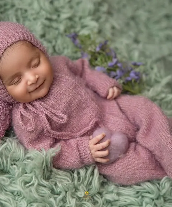 A perfect sleepy smile from a baby dressed in a cozy, knitted lavender outfit. This image embodies the peaceful and gentle nature of my newborn sessions.