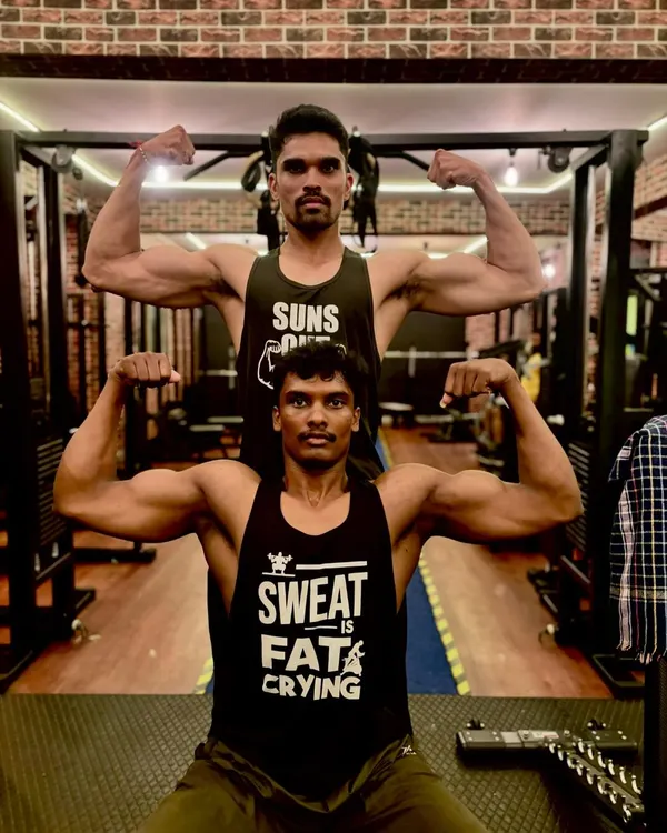 Training partners pushing each other to the next level. Here, two of our members practice a front double biceps pose, showcasing the arm and back development they've achieved together in our gym.