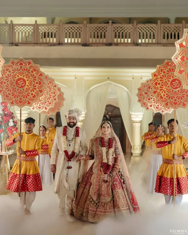 A grand entrance for Rahul and Aashi, walking through a cloud of smoke with traditional umbrellas, creating a truly royal spectacle.