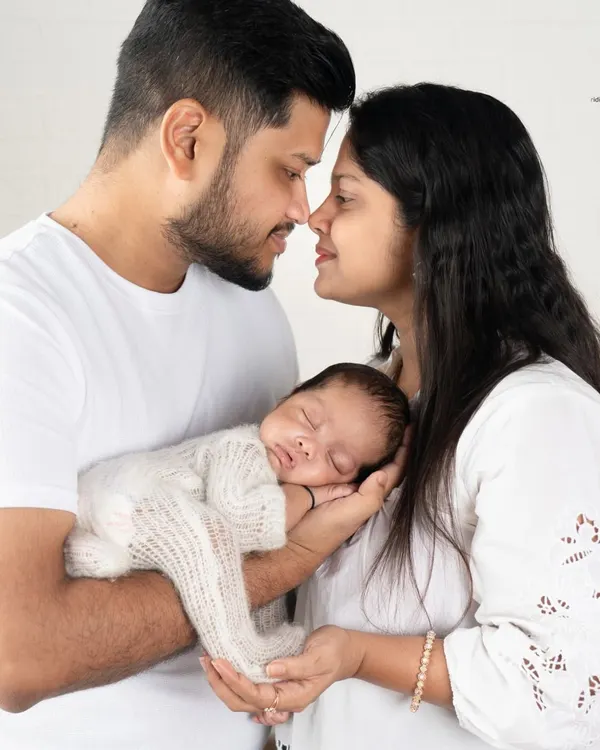 A perfect first family portrait. The baby sleeps peacefully in their parents' hands, a beautiful symbol of how you are their entire world.
