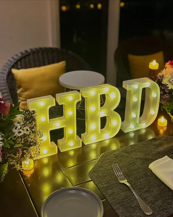 Sometimes, less is more. This minimal table decor with 'HBD' marquee letters, fresh flowers, and candles is perfect for an elegant and intimate birthday dinner.