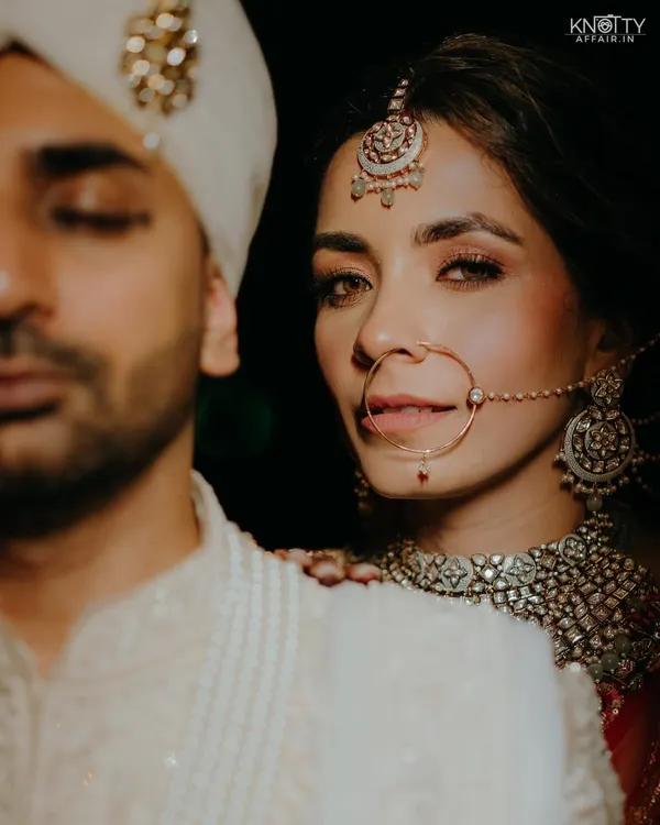 A powerful and intimate portrait from a Dehradun wedding. The bride looks directly at the camera, her gaze confident and captivating, while the groom is in soft focus beside her. It's a moment of quiet connection on their big day.