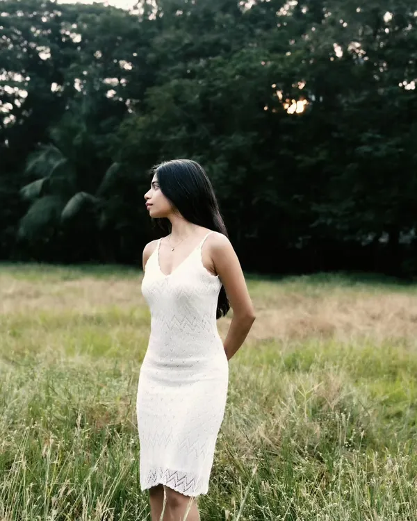A serene portrait in a field of tall grass. The soft, natural light and the simple white dress create a peaceful and timeless look.