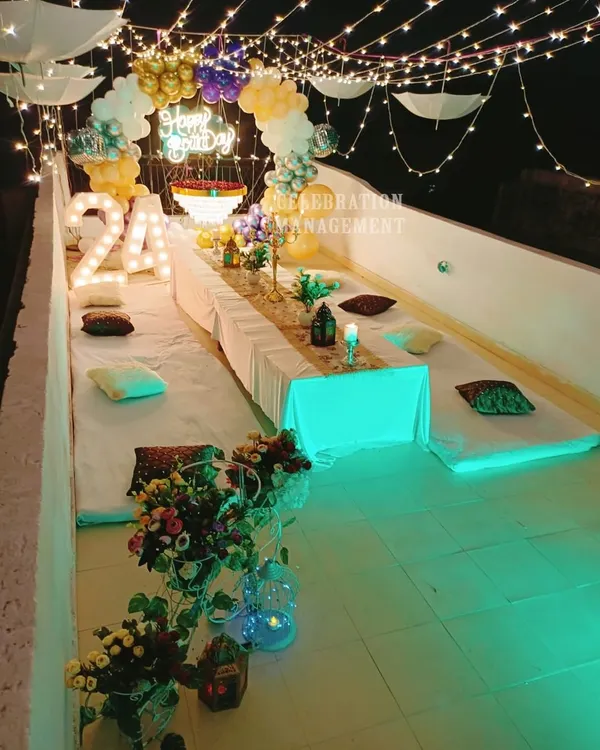 A 24th birthday celebration on a rooftop, complete with low seating for guests, a fairy light canopy, and marquee numbers to mark the special age.