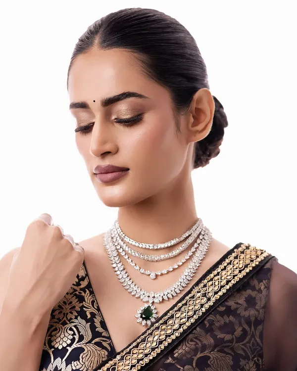 A close-up of a stunning multi-layered diamond necklace with a deep green emerald pendant. This is the epitome of modern glamour, perfect for a reception or black-tie event.