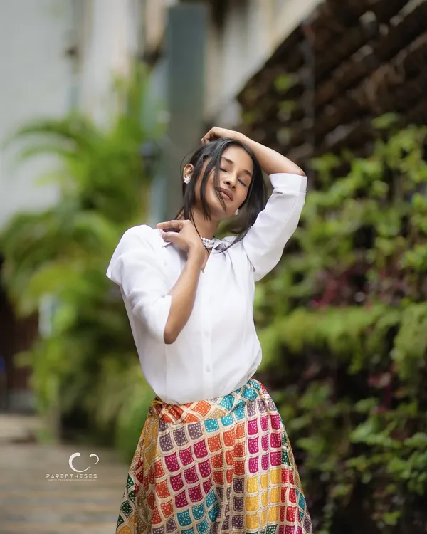 A moment of pure bliss captured outdoors. The soft natural light and the subject's relaxed pose create a feeling of freedom and joy, perfectly contrasting the vibrant skirt with the serene green background.