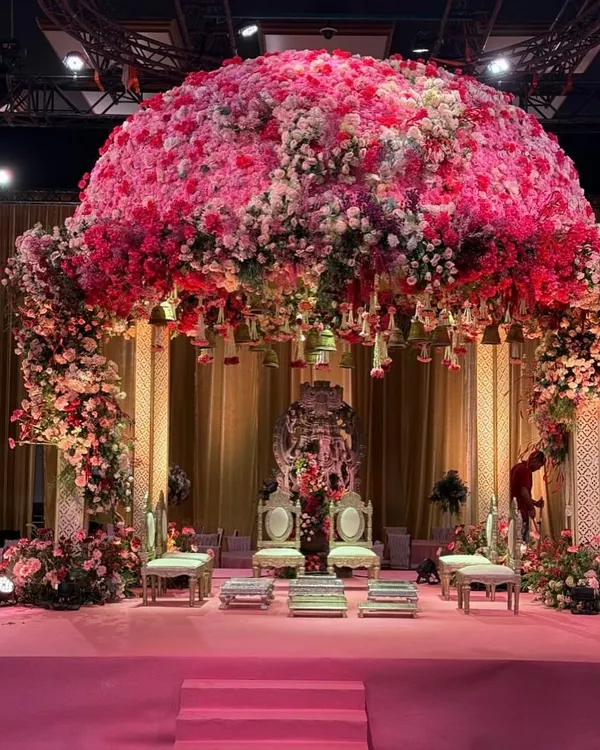 A frontal view of the spectacular 'Gulabi Shaam' mandap, showcasing the sheer density of pink and white florals that form the dome. The design is anchored by a backdrop featuring a Shreenathji idol, blending opulence with divine blessings for the wedding ceremony.