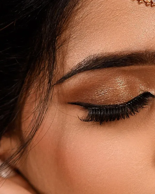 A close up of a classic bronze and gold shimmery eye. This look is perfect for traditional wear, adding warmth and glamour with a sharp winged liner and full lashes.