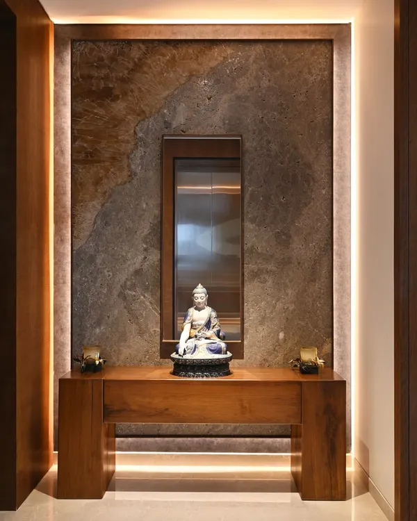 The foyer sets a tranquil tone with a beautiful Buddha sculpture, set against a backdrop of richly textured marble. The design provides a glimpse into the powder room, hinting at the home's cohesive material palette.