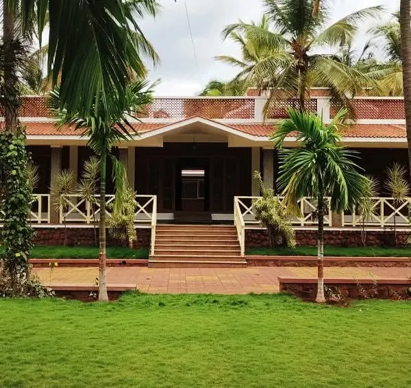 The 'Grid in the Grove' farmhouse was designed to be in complete harmony with its surroundings. The facade, with its terracotta roof and traditional details, is perfectly framed by the coconut and areca nut palms.