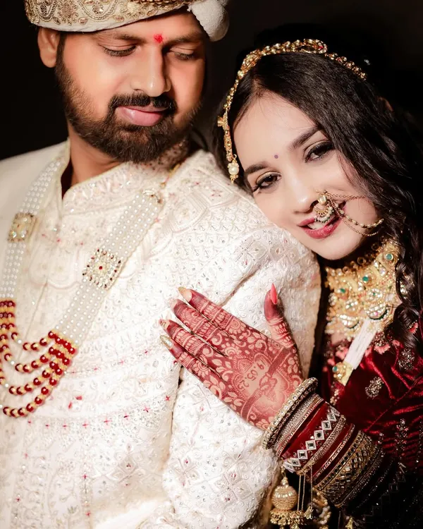 An intimate close-up of the bride resting her head on the groom's shoulder. The focus on her detailed mehndi and the couple's serene expressions makes this a beautifully romantic wedding portrait.