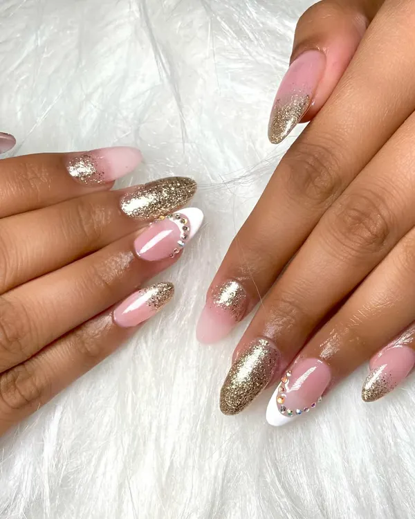 A beautiful set of almond-shaped acrylic extensions. This design features a classic French ombre with a touch of gold glitter and delicate rhinestone accents for a bit of sparkle.