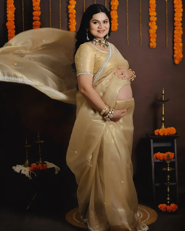 This is one of my favorite shots, capturing the timeless elegance of motherhood with a traditional Indian theme. The flowing golden organza saree and authentic props like marigold garlands and brass diyas create a truly special portrait.