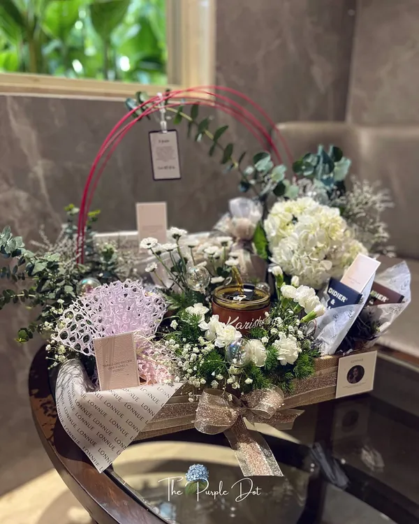 The complete view of a reimagined brand launch gift. Centered around a personalized candle and surrounded by hydrangeas and other curated items, this hamper tells a story of resilience and elegance.