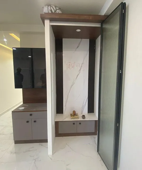 A compact and elegant pooja unit designed with a marble-finish back panel and integrated storage, seamlessly fitting into the home's modern aesthetic.