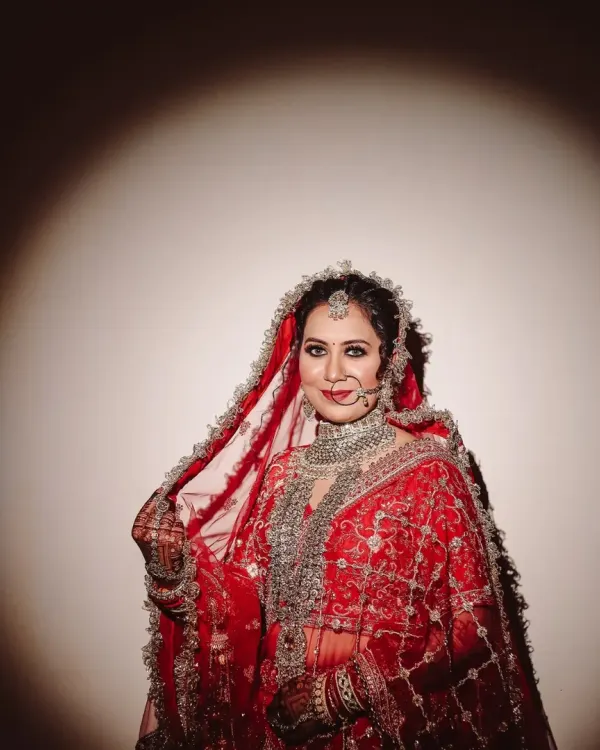 A spotlight moment for the bride. I used dramatic lighting to sculpt this portrait, making her red lehenga and intricate jewelry stand out against the dark, creating a powerful and painterly effect.