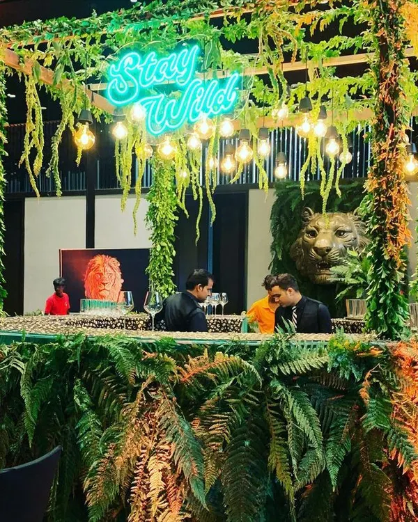 I designed this "Stay Wild" bar for a President's Gala, transforming a standard venue into a lush jungle. The custom neon sign and dense foliage create an immersive atmosphere perfect for a high-end corporate event.