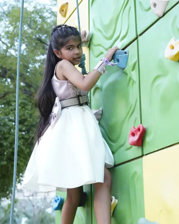 Adventure comes in all forms, even in a party dress! This young climber shows her strength and determination on our colorful outdoor climbing wall.